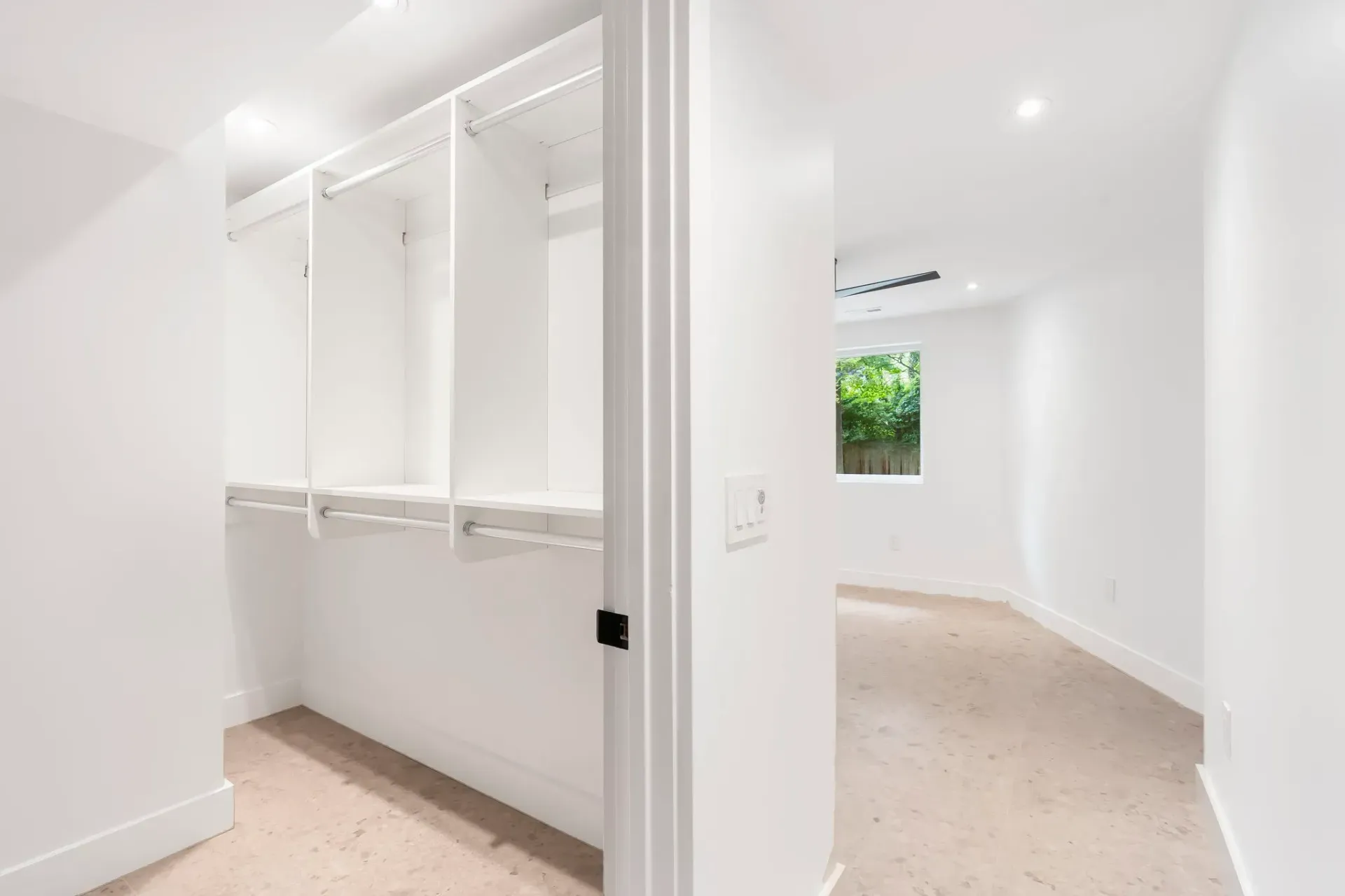 Bright white hallway with built-in cabinets and a small window showing greenery.