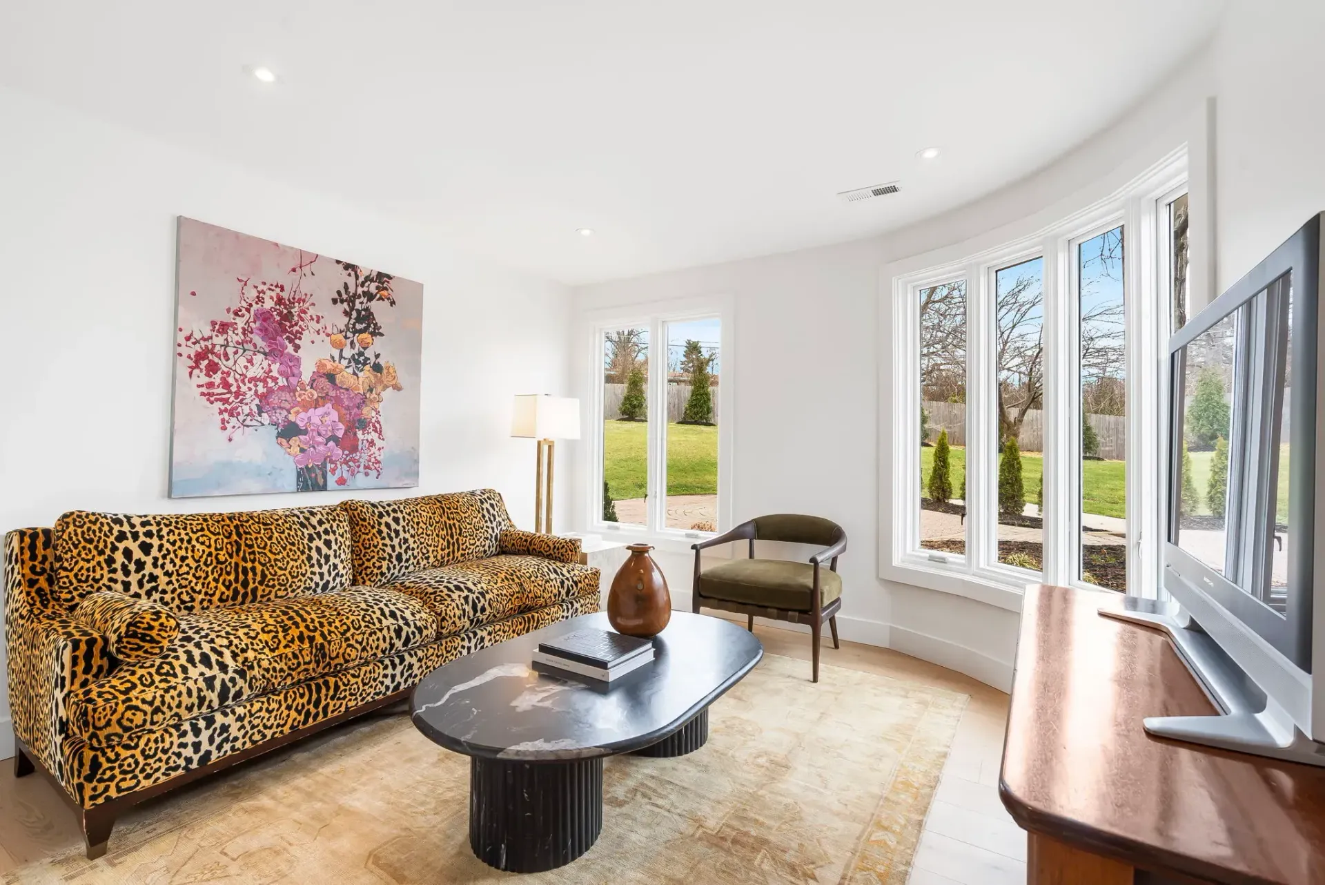 Bright living room with leopard-print sofa, piano, large windows, and colorful wall art