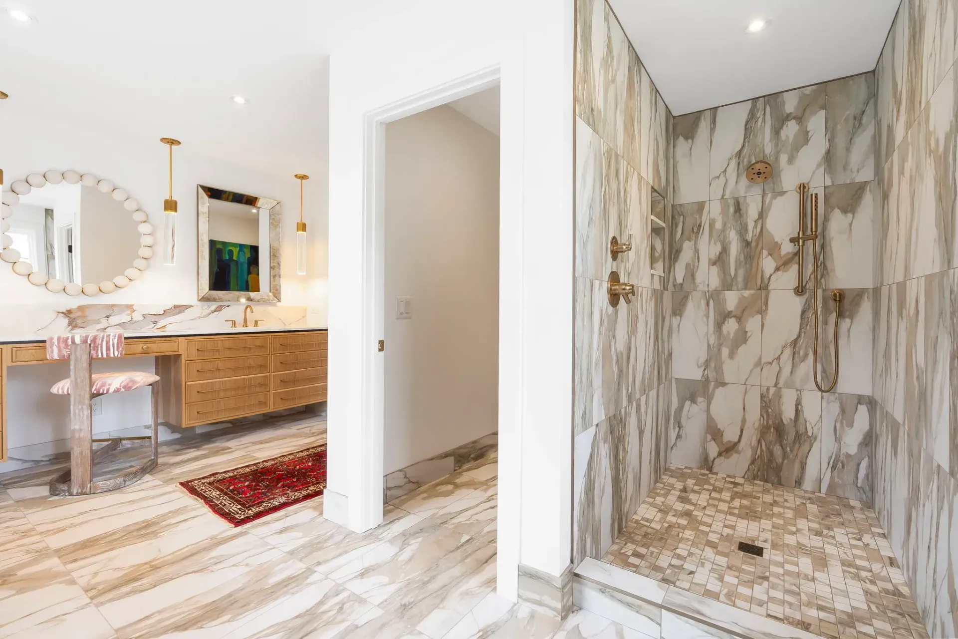 Luxury bathroom with marble shower, vanity mirror, and cream-and-gold tile accents