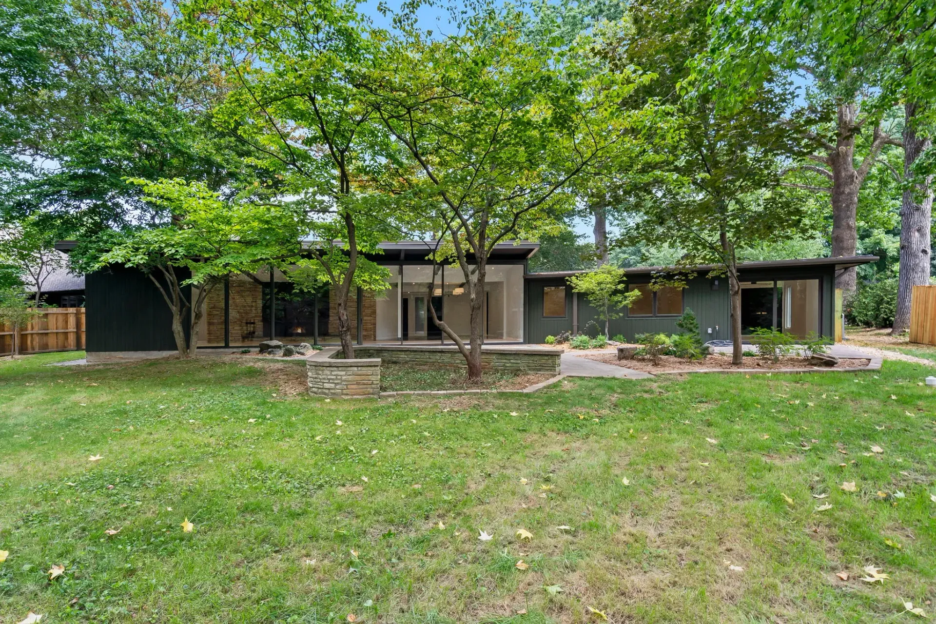Tree-shaded house with a large grassy yard and stone patio in front
