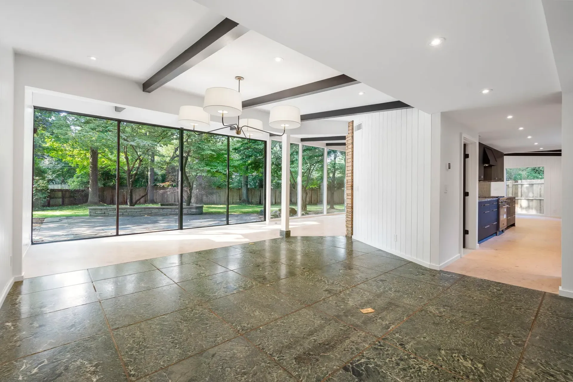 Modern empty living room with polished floor, large glass doors, and garden view