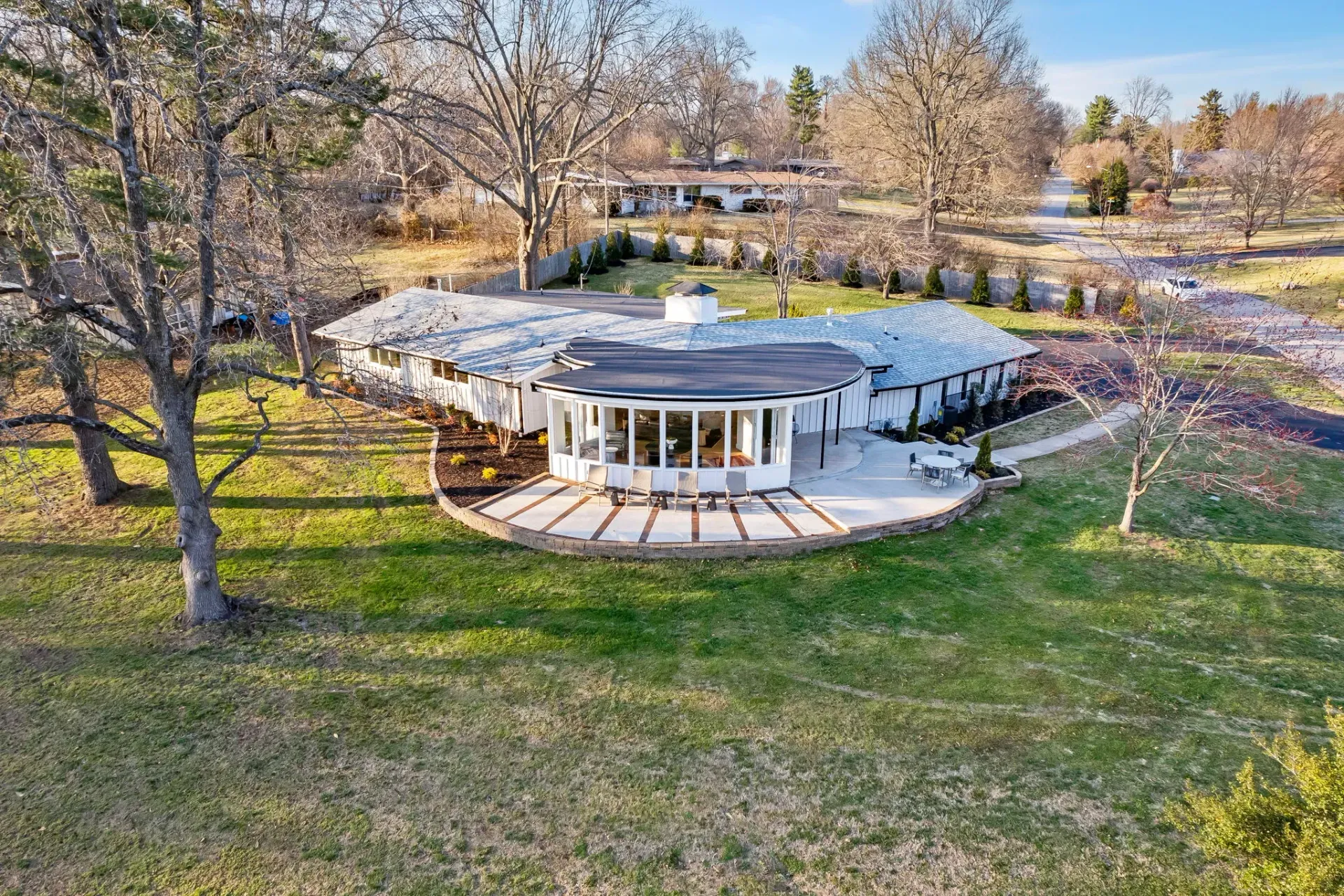 Aerial view of a round white pavilion in a grassy park with trees and spring flowers.