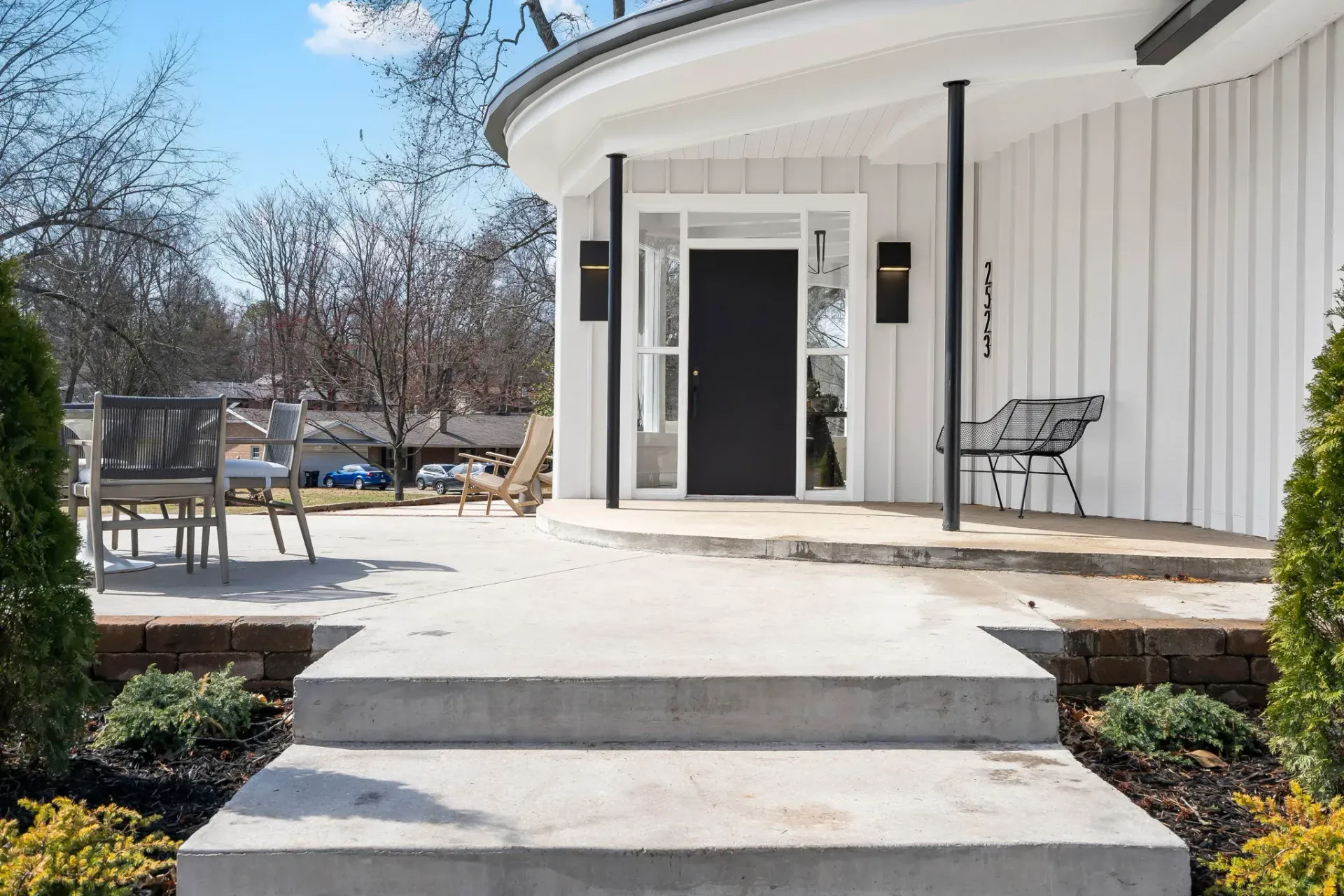 Accessible building entrance with a ramp, open white doors, and outdoor seating on a sunny day