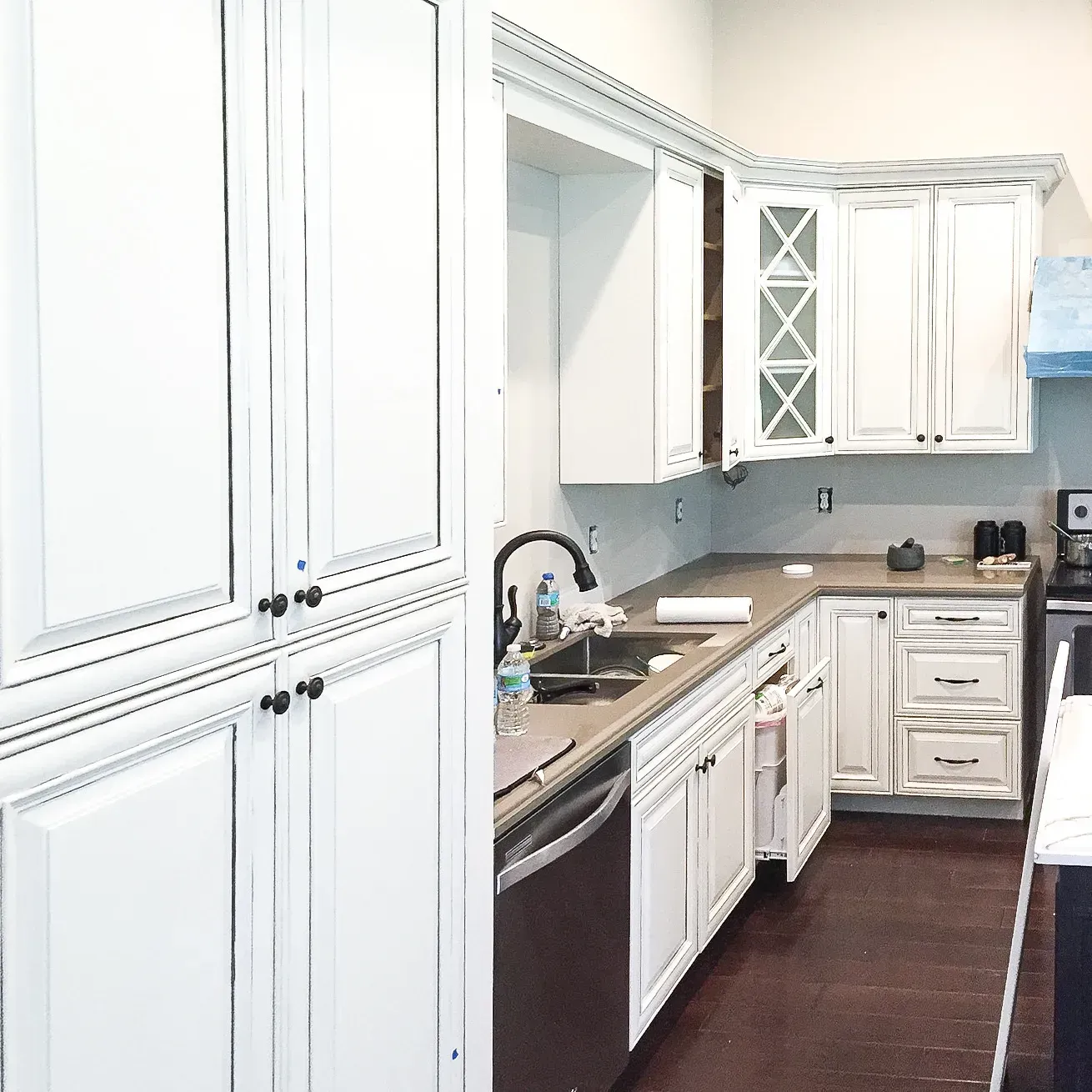 Bright white kitchen with cabinets, sink, dishwasher, and dark countertops along a narrow galley layout