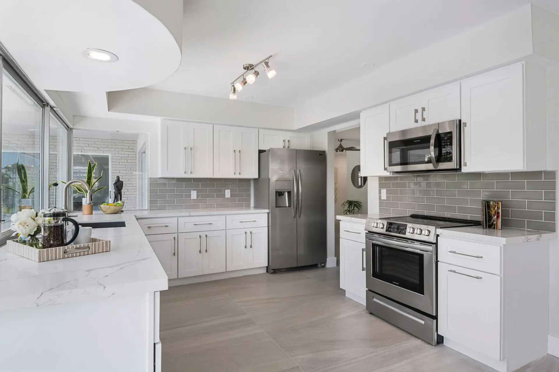 Bright modern white kitchen with stainless steel appliances, island, and tile backsplash
