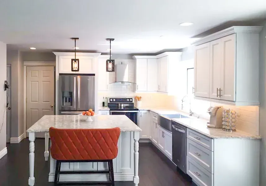 Bright modern kitchen with white cabinets, stainless appliances, and an orange quilted bar stool