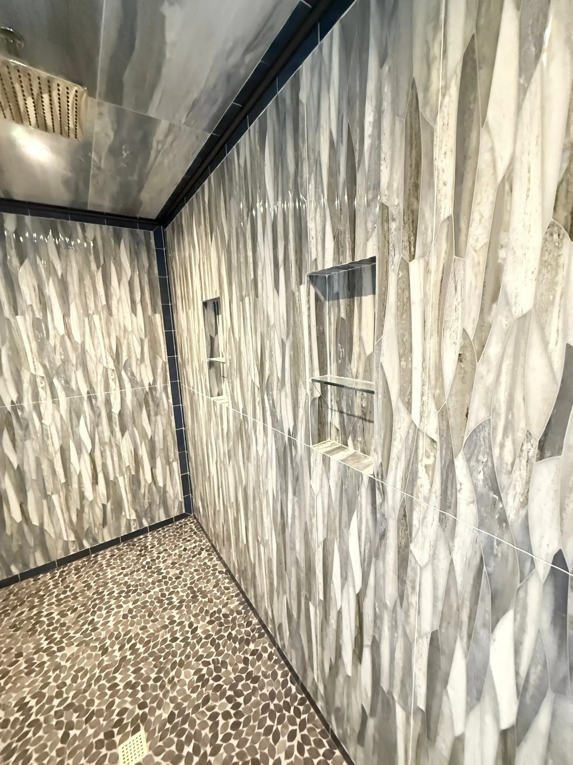Narrow hallway with gray marble-patterned walls, speckled floor, and small wall-mounted fixtures.