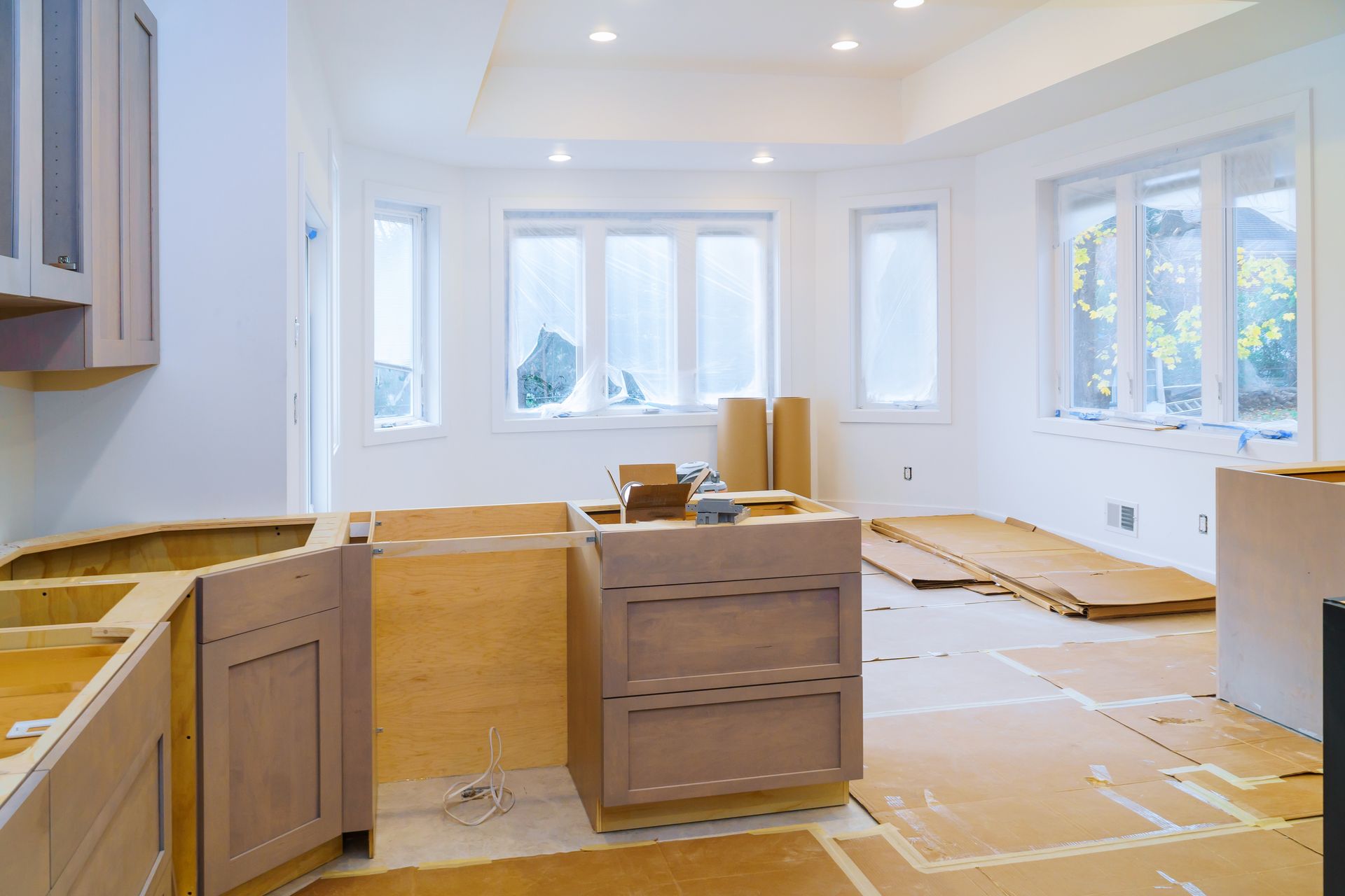 Kitchen remodel in progress with base cabinets installed and protected flooring