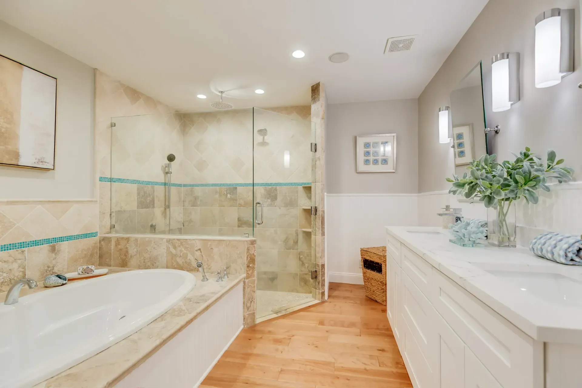 Bright modern bathroom with tub, glass shower, white vanity, wood floor, and recessed lighting