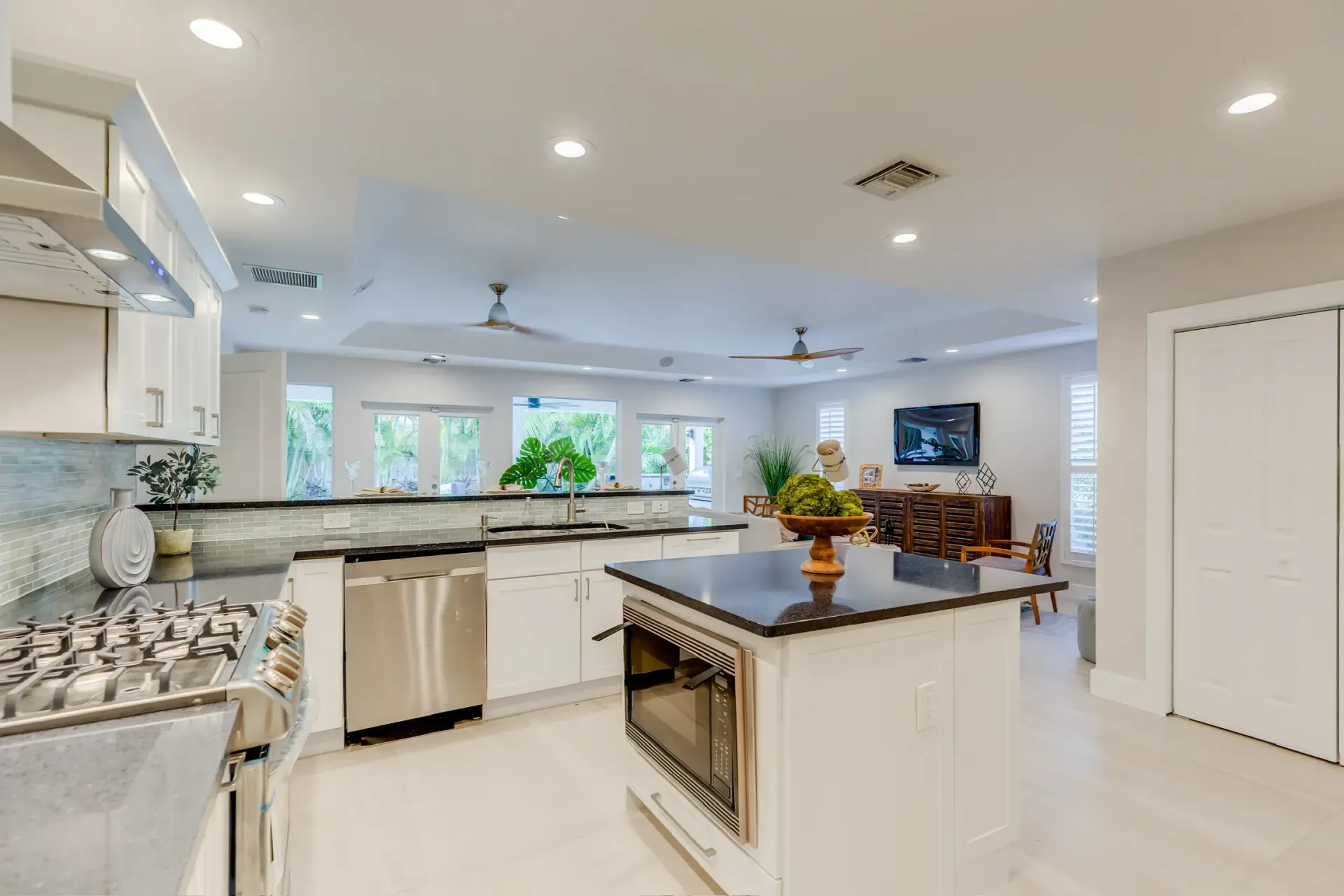 Bright modern kitchen with white cabinets, black countertops, stainless appliances, and island seating