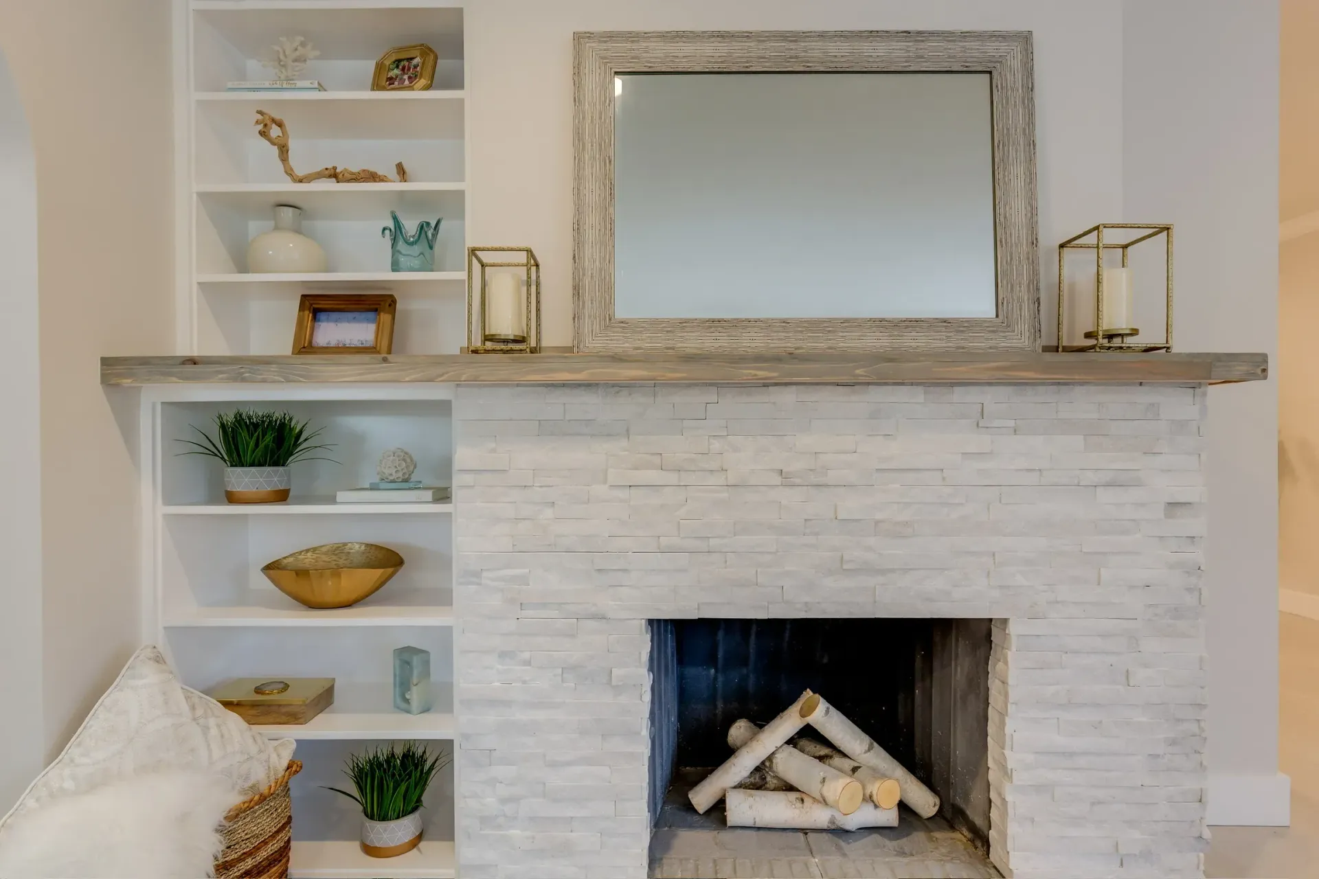 Bright living room fireplace with white shelves, decor, and a large mirror above the mantel