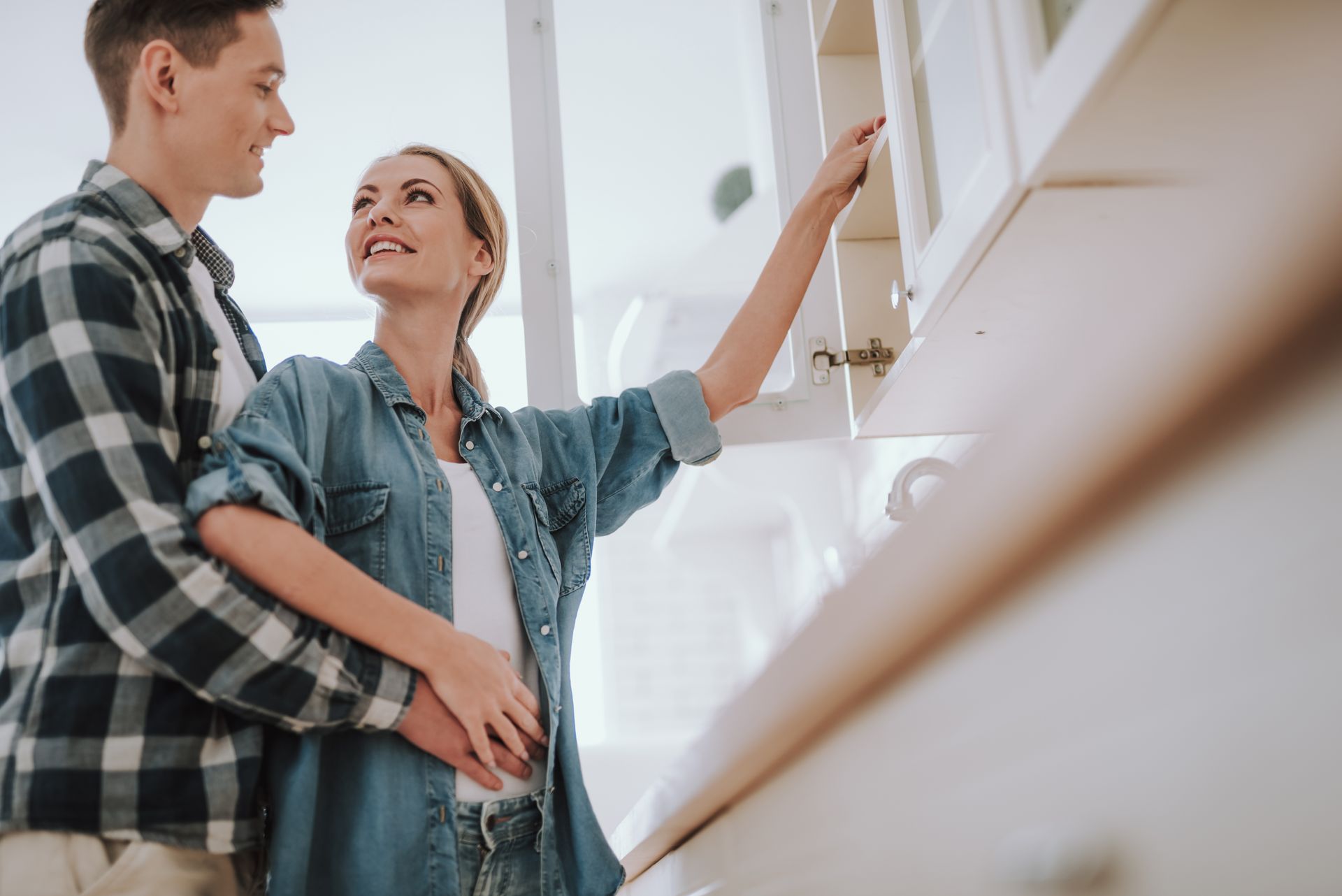 Couple reviewing kitchen cabinets, comparing storage, fit, and design options in a bright kitchen