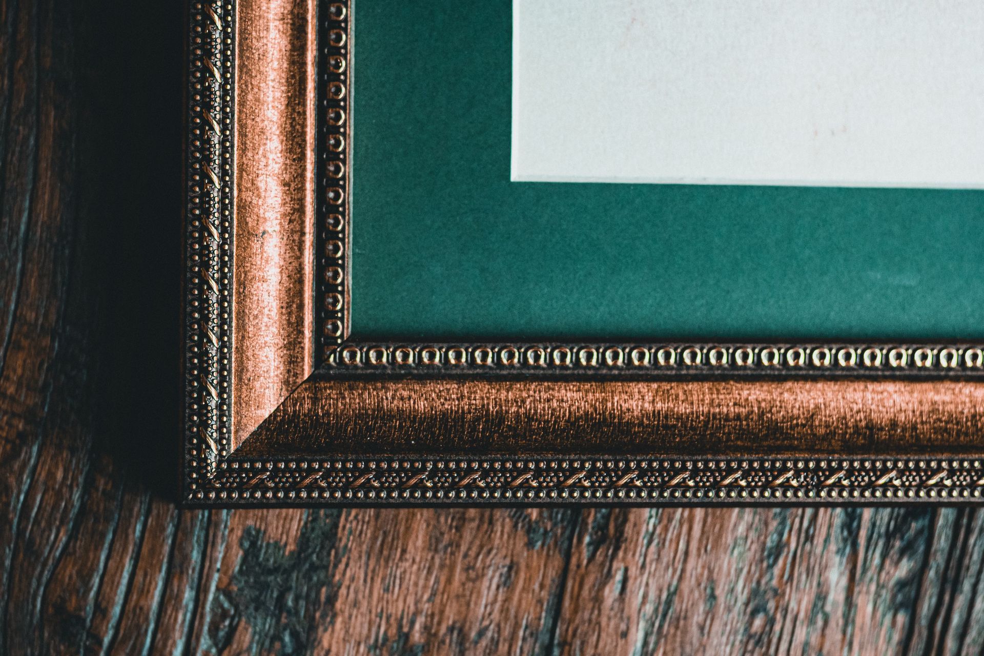 Close-up of a gold ornate frame on teal mat at Caruso in Springfield, MO