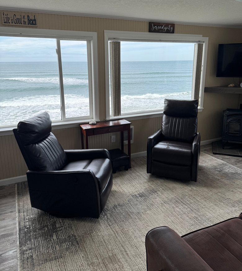 A living room with two chairs and a table with a view of the ocean