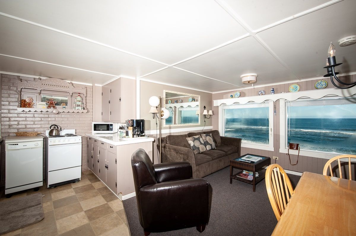 A living room with a couch , chairs , and a table with a view of the ocean.