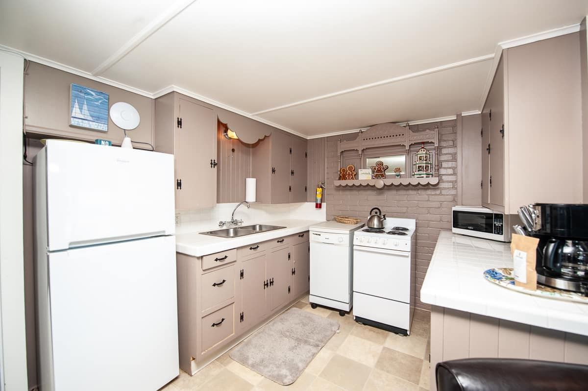 Compact beige kitchen with white fridge, stove, sink, and countertop appliances.