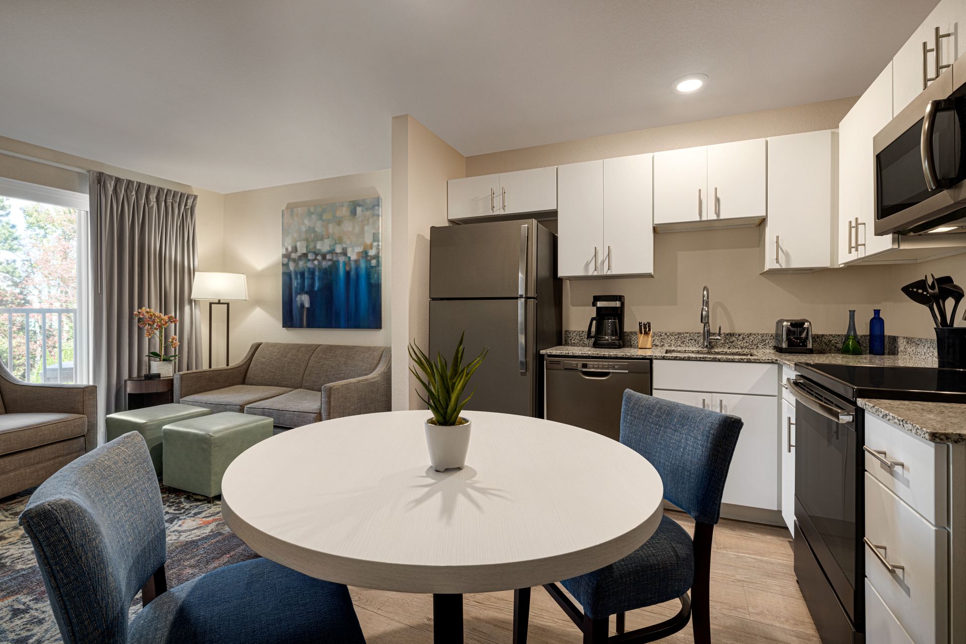 A kitchen and dining room in a hotel room with a table and chairs.