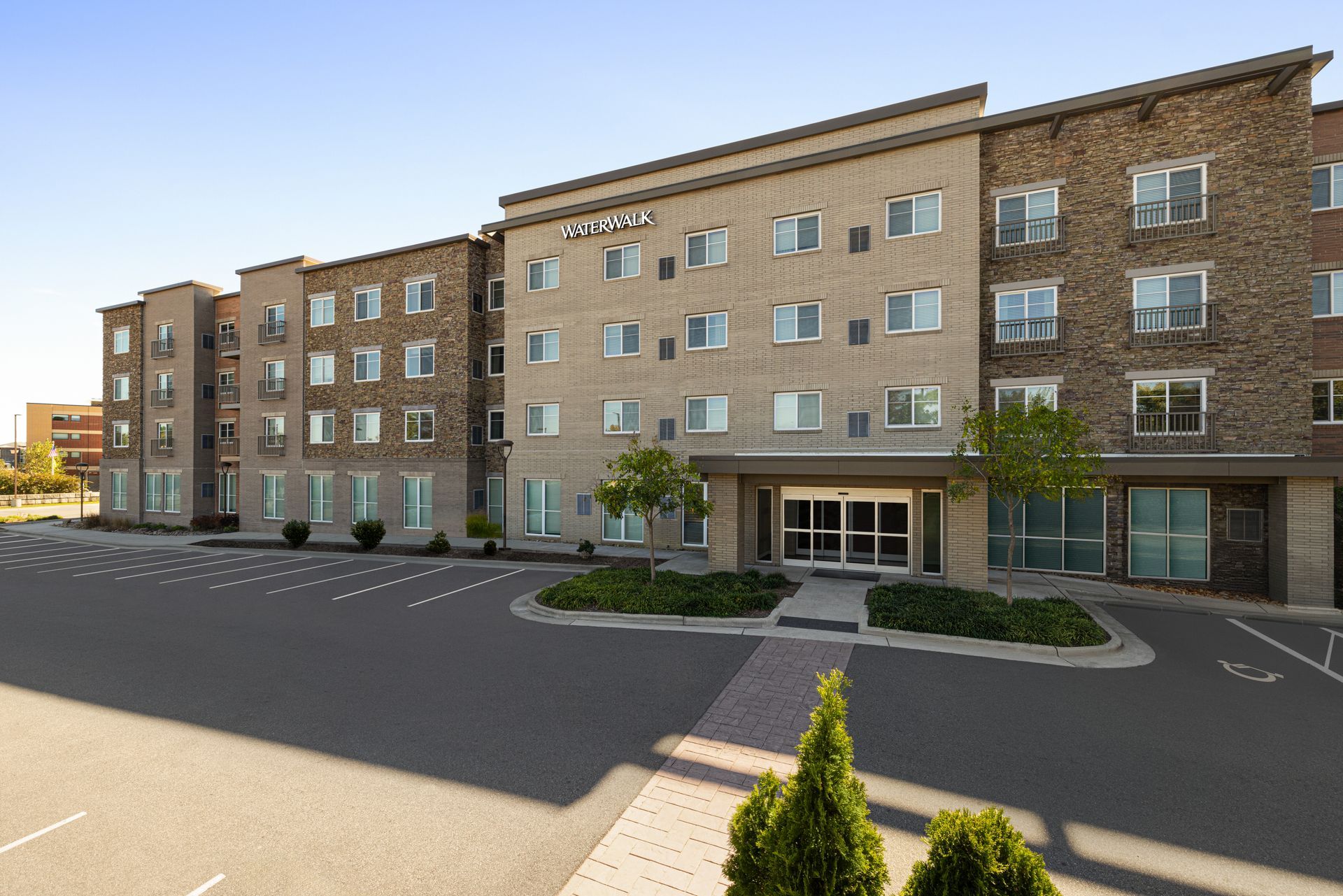 A large building with a lot of windows and a parking lot in front of it