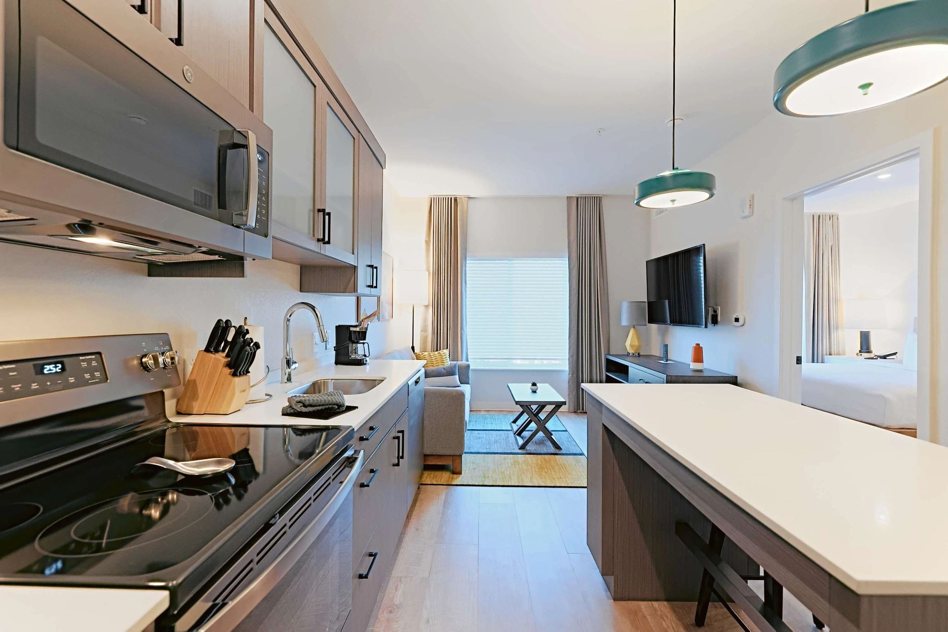 A kitchen with a stove , sink , microwave and television.