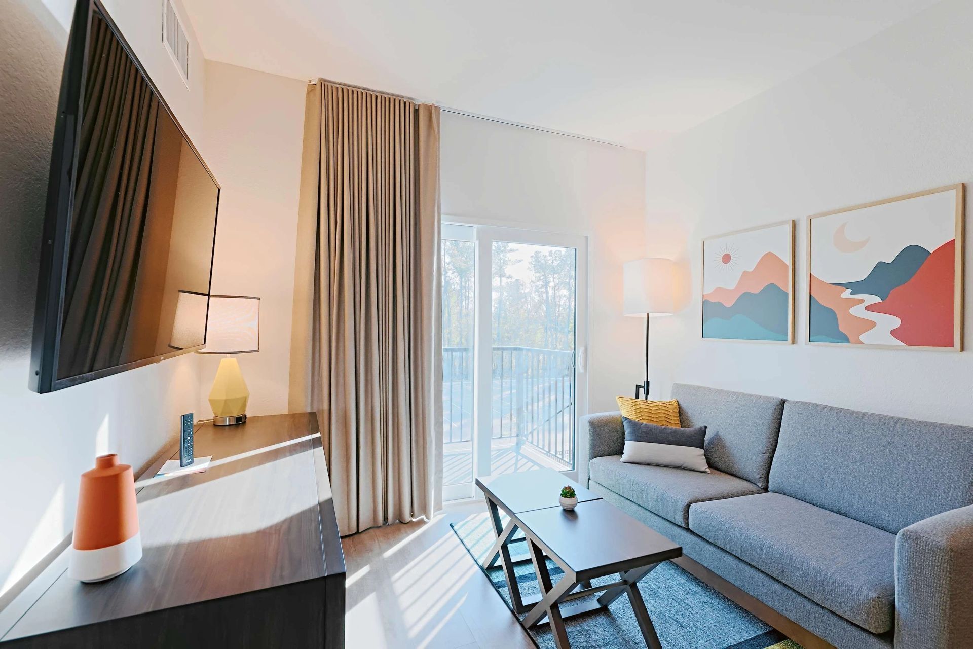 A living room with a couch , table , television and balcony.
