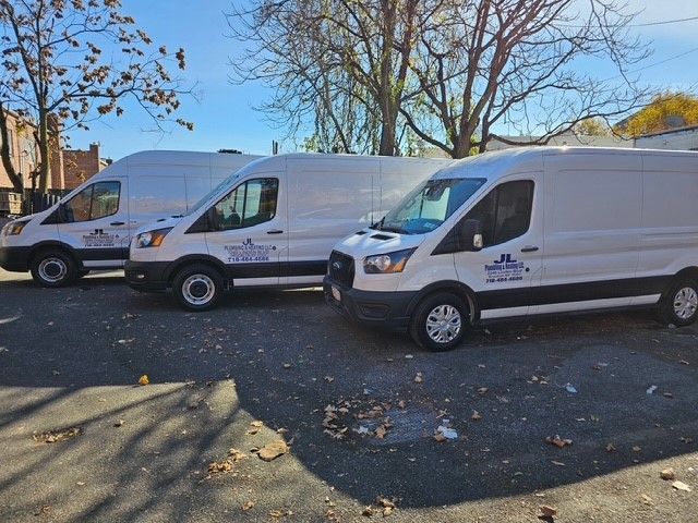Three white vans are parked next to each other in a parking lot.