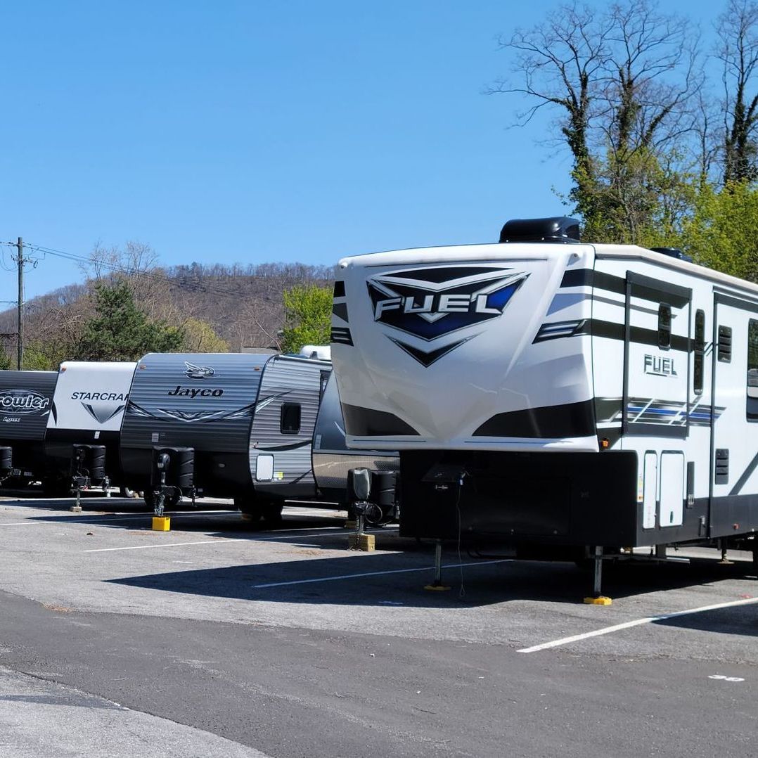a row of recreational vehicles are parked in a parking lot