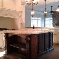 Luxury kitchen island with dark wood base, marble top, and hanging pendant lights