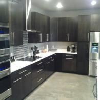 Modern kitchen with dark cabinets, white countertops, and stainless steel appliances