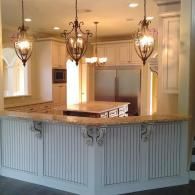 Elegant kitchen with white cabinets, wood island, and three hanging pendant lights