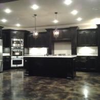 Modern dark kitchen with black cabinets, white countertops, and recessed ceiling lights