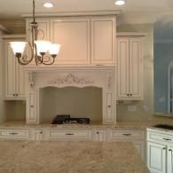 Elegant cream kitchen with ornate cabinets, chandelier, and granite island countertop