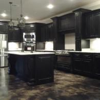 Dark kitchen with black cabinets, white countertops, and a central island.
