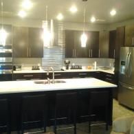 Modern kitchen with dark cabinets, stainless steel appliances, and a large white island countertop.