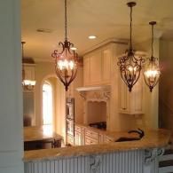 Warmly lit foyer with ornate hanging chandeliers and a stairway overlook.