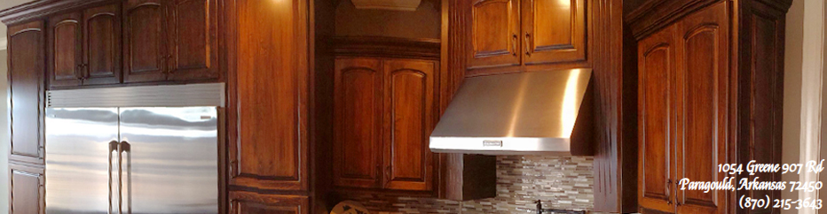 Wooden kitchen cabinets, stainless steel refrigerator, and range hood in a warm-toned kitchen