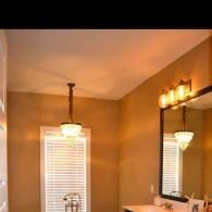 Warm beige bathroom with a window, vanity mirror, and ceiling light fixture