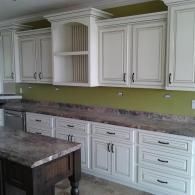 White kitchen cabinets with gray countertops and a green wall backsplash.