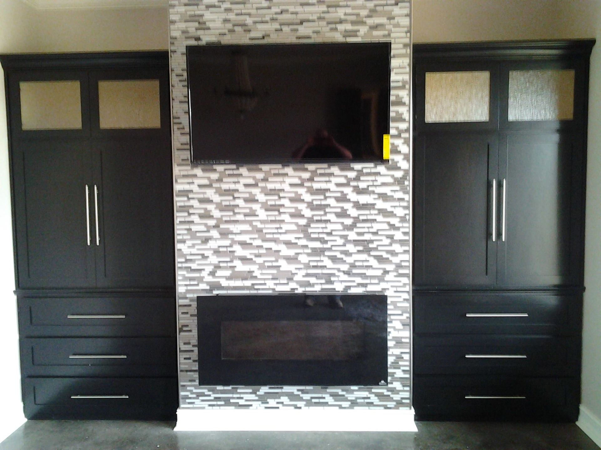 Living room wall with built-in fireplace, TV, and two black cabinets with drawers