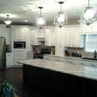 Bright modern kitchen with white cabinets, large island, and hanging pendant lights