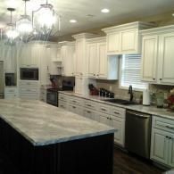 Bright kitchen with white cabinets, large island, pendant lights, and stainless steel appliances