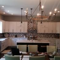 Modern kitchen with cream cabinets, mosaic backsplash, island, chandelier, and dining chairs