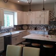 Modern kitchen with white cabinets, mosaic backsplash, marble island, and two pendant lights
