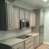 Modern kitchen with light gray cabinets, stainless steel appliances, and pale countertops