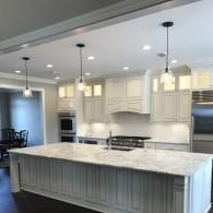 Bright modern kitchen with white cabinets, marble island, and hanging pendant lights