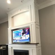 Flat-screen TV mounted above a white fireplace in a gray living room.