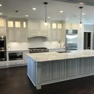Bright modern kitchen with white cabinets, large island, stainless steel appliances, and dark wood floors