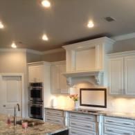 Modern kitchen with white cabinets, granite island, stainless double oven, and recessed ceiling lights