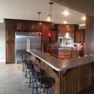 Spacious kitchen with stainless steel appliances, dark wood cabinets, and a granite breakfast bar with stools