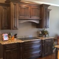 Dark wood kitchen cabinets with granite countertop and built-in range hood.