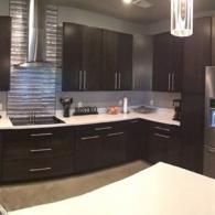 Modern kitchen with dark cabinets, stainless steel appliances, and a light countertop